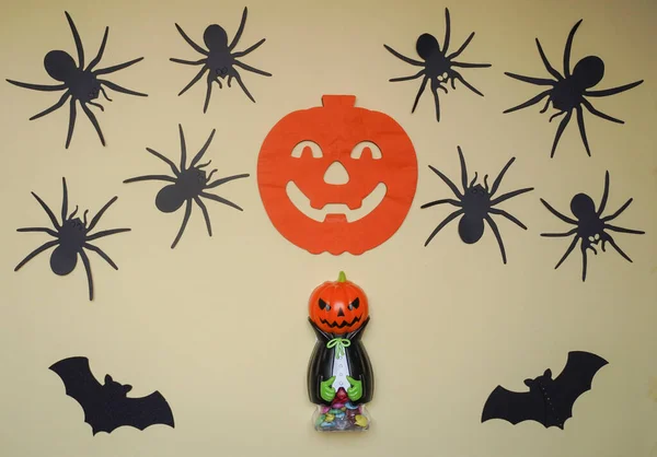 Scary Halloween figurines stand on a light background in close-up, behind hangs terrible pumpkin, spiders and bats. Cute character in monster costume. Halloween concept. Holiday decorations toys