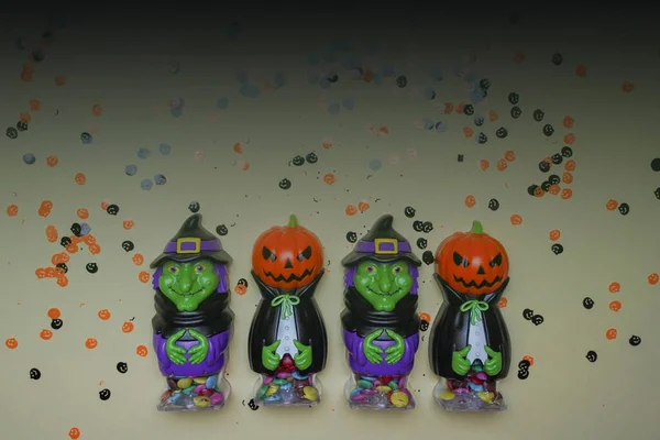 Terrible figures of witches and monsters on a light background strewn with colorful confetti. The concept of the Halloween holiday. Festive figurines. Halloween decorations.