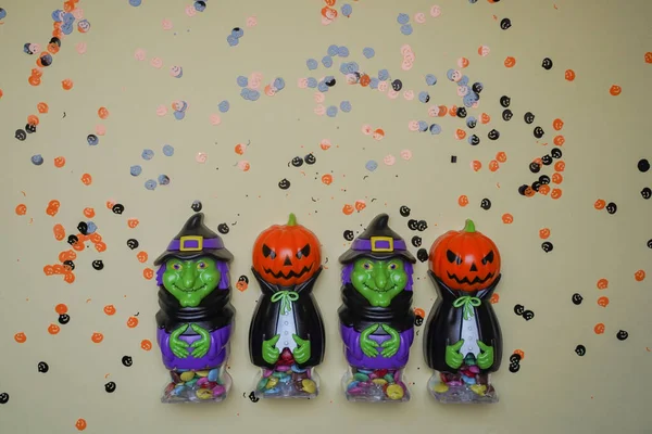 Terrible figures of witches and monsters on a light background strewn with colorful confetti. The concept of the terrible Halloween holiday. Festive figurines. Empty space. Halloween decorations.