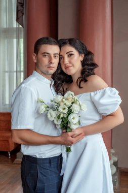 The bride gently snuggled up to the groom. Happy bride and groom. Portrait of a man and a woman in a white vintage dress in a classic interior on a wedding day. Wedding day