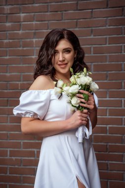 Beautiful bride with wedding bouquet on brown brick wall background