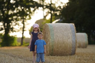 İki çocuk gün batımında saman tarlasında erkek ve kız kardeş.
