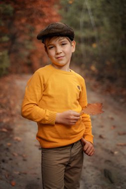 Children's fashion, retro style. A smiling little boy in a retro style coat and cap stands and smiles. Copy space.