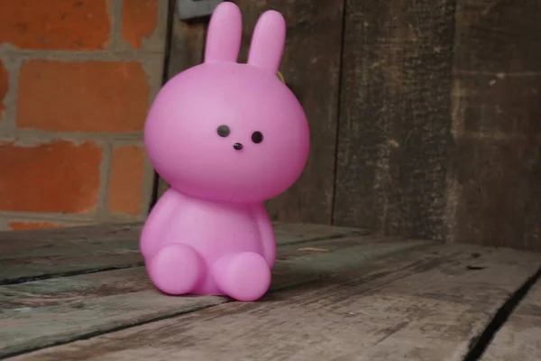 Pink toy plastic rabbit on a wooden background with copy space. Eco-friendly toys. The concept of Easter.