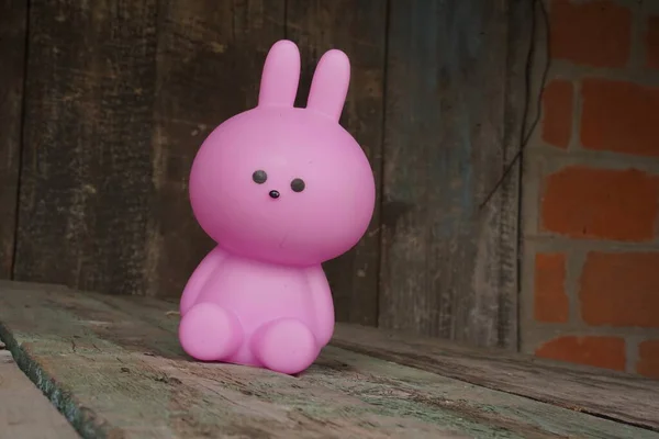 Pink toy plastic rabbit on a wooden background with copy space. Eco-friendly toys. The concept of Easter. Selective focus.