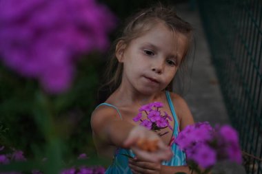 Young pretty girl in closed eyes enjoys the smell of lilac in the early morning in the garden. Selective focus.