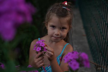 Young pretty girl in closed eyes enjoys the smell of lilac in the early morning in the garden. Selective focus.