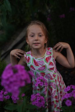 Young pretty girl in closed eyes enjoys the smell of lilac in the early morning in the garden. Selective focus.