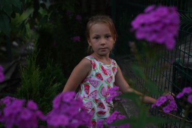 Young pretty girl in closed eyes enjoys the smell of lilac in the early morning in the garden. Selective focus.