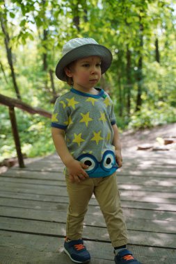 A child with a mosquito on his forehead in the woods on a path in the summer.