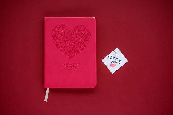A book and a note with the words I love you, the best gift for a book lover. Valentine's Day, declaration of love. On a red background, the color of love and passion. DIY concept.