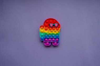 Colorful trendy pop it toy in form a character among us with heart-shaped glasses. Valentine's Day background. Very Peri background color. Flat lay, copy space.