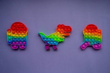 Fashionable pop toys in the form of a dinosaur, and a character among us on a Very Peri background