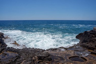 Akdeniz kıyılarındaki İncekum Doğal Parkı yakınlarındaki kayalara dalgalar çarpıyor. Gökyüzü mavisi su. Seçici odak.