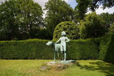 Montana Körfezi, ABD - 12 Ağustos 2022: pitoresk yeşil bir bahçede büyük bir köpeği olan bilinmeyen bir kızın heykeli. Bilinmeyen heykeltıraşın anıtı. Bahçe dekoru