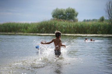Yaz tatilinde sahilde koşan mutlu çocuk. Çocuk dışarıda oynuyor. Seçici odak.