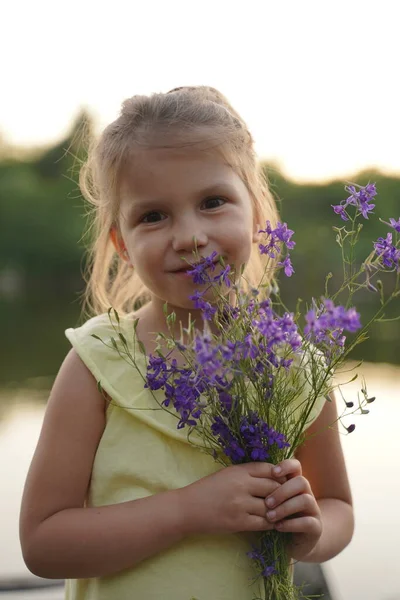 一个女孩手里拿着一束野花 女孩把脸藏在一束狼疮后面 小女孩在开花的田野里抱着一大束紫色的羽扇豆 自然概念 有选择的重点 — 图库照片