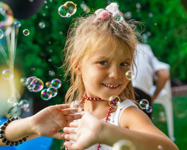 在孩子们的聚会上 一个女孩在肥皂泡里跳舞 夏天孩子们的生日聚会在后院举行 泡沫中的美 — 图库照片