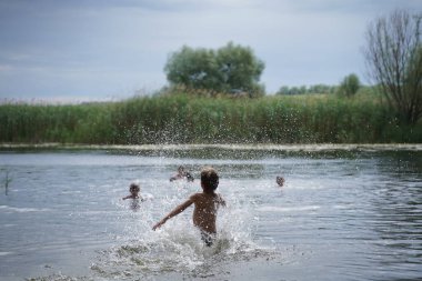 Sahilde su sıçratmaca oynayan eğlenceli çocuklar. Seçici odak.