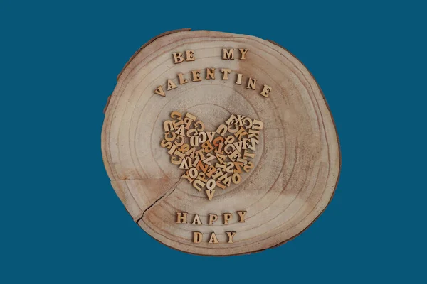 Wood heart isolated on blue background. Timber wood piece in heart shape - love in nature concept. Wooden stump desk. Tree slice in heart form. Brown wood board as signboard top view.