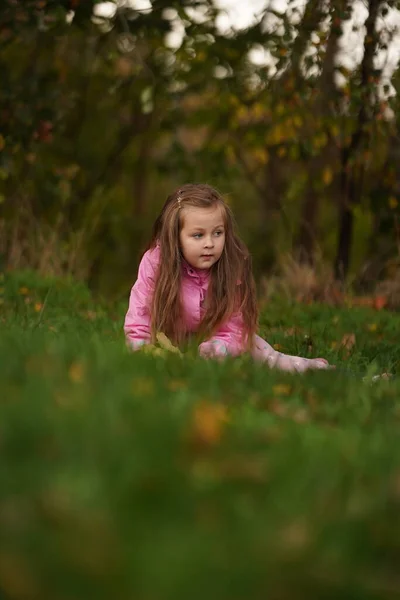 一个微笑的小女孩躺在绿草上的画像 有选择的重点 — 图库照片