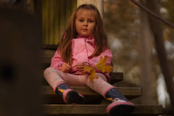一个红头发的女孩坐在房子的木制台阶上 背对着棕色的背景 抬起头做梦 有选择的重点 — 图库照片