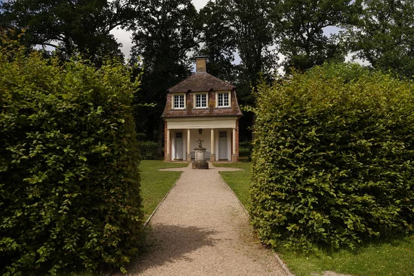 stock image A charming playhouse cottage sits at the edge of a shaded perennial garden.