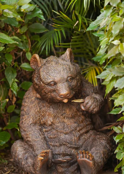 A bronze bear sits in tropical foliage. Travel concept. Wildlife protection. Bear statue in nature.