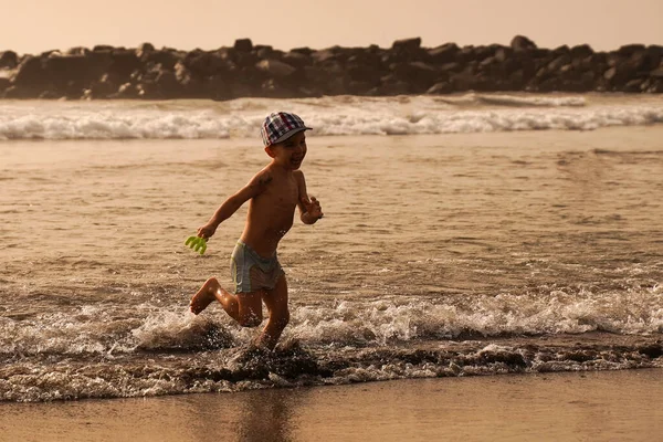 Stock image Little boy running merrily on the waves. A family vacation on a tropical island.