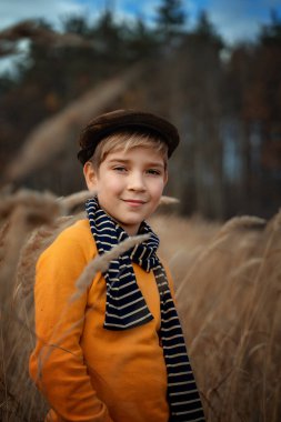 Children's fashion, retro style. A smiling little boy in a retro style coat and cap stands and smiles. Copy space.