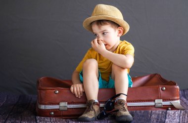 Bavulun üzerinde yaz kıyafetleri içinde bir çocuk. Kıpır kıpır bir yaz gezisine hazırlanıyor. Rüya gören bebek