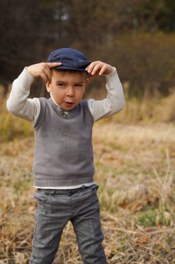Doğada eski giysiler içinde neşeli bir çocuk.