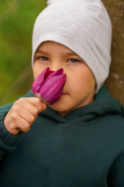 Bambino Carino Seduto Nel Giardino Autunnale Annusare Bocciolo Viola Tulipano — Foto Stock