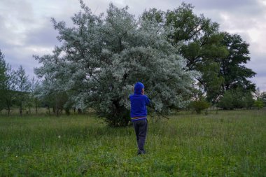 Büyük bir ağacın arka planında, dikiz manzaralı yalnız bir genç. Gençlik yalnızlığı