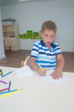 Çocuk renkli kalemlerle resim çiziyor. Erken gelişim kavramı