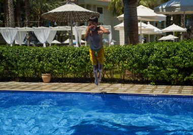 Havuzun üzerinde uçan bir çocuk. Tropik eğlence tatili