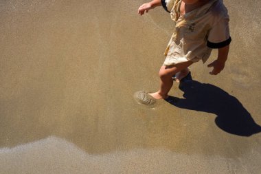 Sahildeki kumda çıplak ayaklı bir çocuk, Top View. Yaz tatili