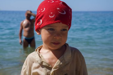 Ağlayan gücenmiş çocuk yakın plan, ve bulanık arka planda şefkatli baba. Baba oğlunu gücendirdiği için pişman. Berbat bir yaz tatili. Babalar ve oğullar