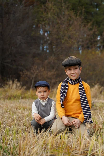 Δύο Μοντέρνα Παιδιά Που Κάθονται Ένα Φθινοπωρινό Χωράφι Μοντέρνα Ρούχα — Φωτογραφία Αρχείου