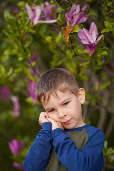 一个小男孩在紫色花朵的衬托下 双手交叉地做梦 小男孩梦想着 微笑着 — 图库照片
