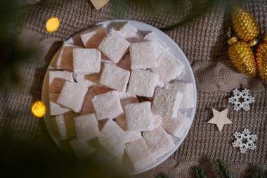 Ladin dallı ve bokeh ışıklı bir tabakta şekerlemeler.