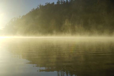 Foggy mountain lake covered with sunlight and yellow haze in Bromo Tengger Semeru National Park, Indonesia