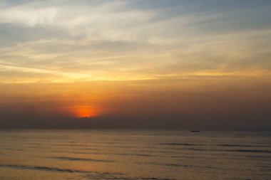 Sakin bir okyanusta güneşin doğuşunun doğası.