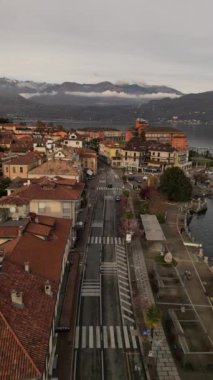İtalya 'nın kuzeyindeki Stresa Lago Maggiore' a giden dikey İHA video uçuşu, geleneksel kırmızı çatı binalarıyla çevrili ana göl yolunda hareket eden araçlar.  