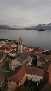 Stresa 'nın Lago Maggiore' daki dikey videosu. Geleneksel İtalyan kırmızı çatıları ve saat ve göl manzaralı taş şapeli.