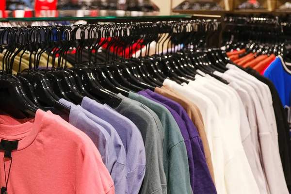 Many colored T-shirts on a hanger in a clothing store. Seasonal clothing sale.