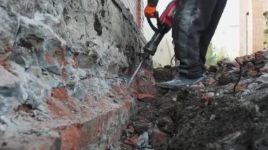 İşçiler eski bir temeli kırmak için elektrikli matkap kullanıyorlar. Yeni bir konut inşaatı.
