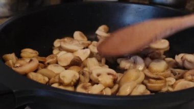 Bir aşçının gaz sobasında tavada mantar kızartırken yakın çekimi. Sağlıklı yemek pişirmek..