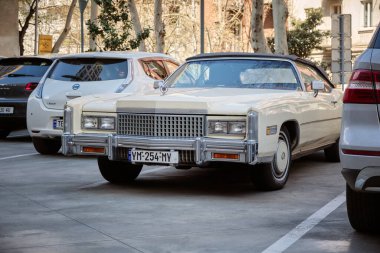 Şehirdeki diğer modern arabaların yanındaki otoparktaki bej renkli Cadillac 'ın güzel retro arabası: Tiflis, Georgia - 29 Mart 2023