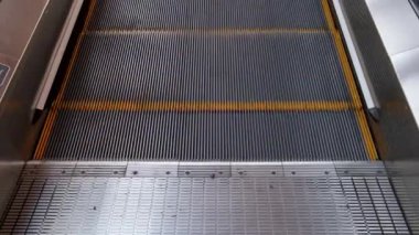 Yürüyen merdivenin basamaklarının hareketi. Bir adam iş merkezinde, alışveriş merkezinde ya da havaalanında yürüyen merdivene tırmanır..